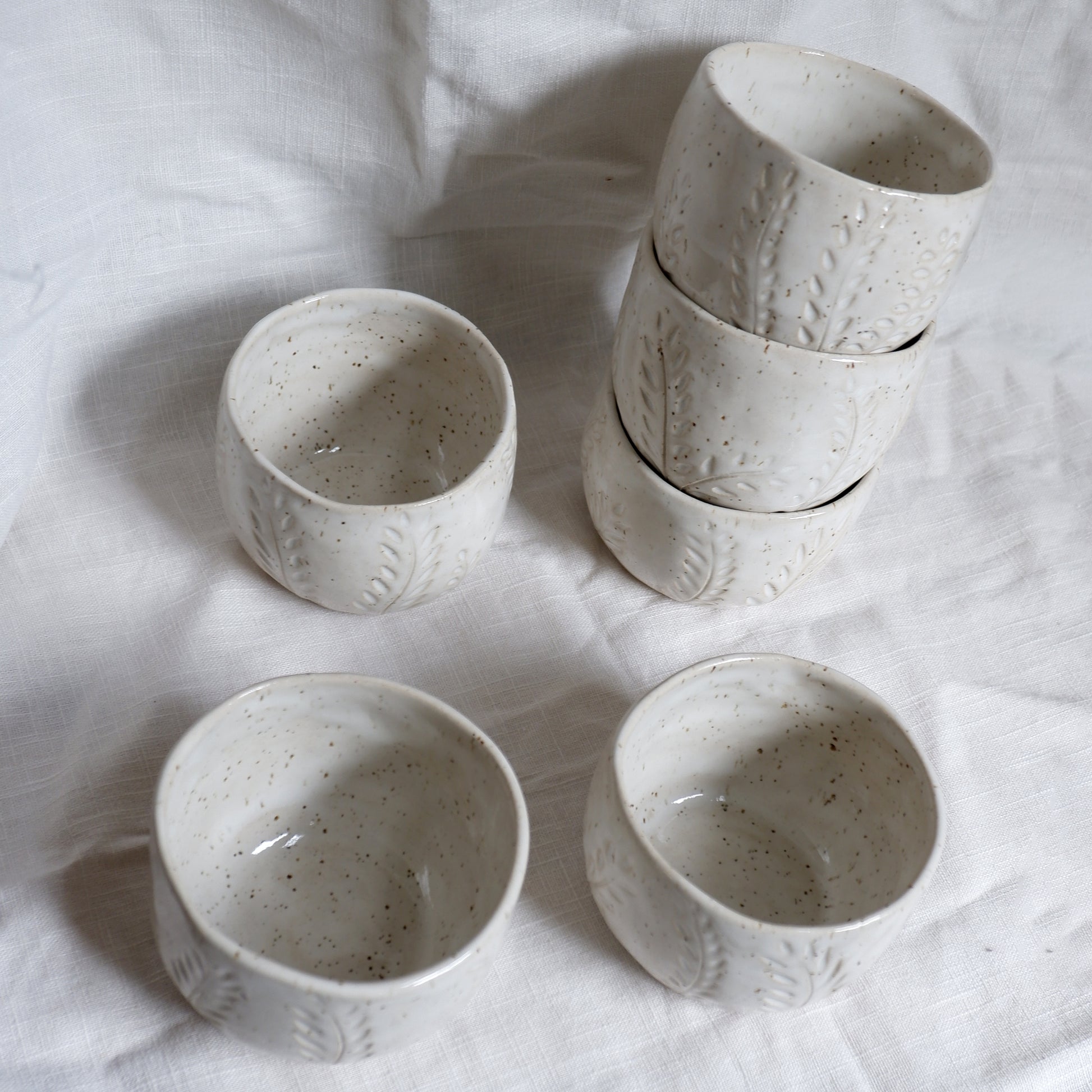 Set of ceramic bowls and cups on a white fabric background