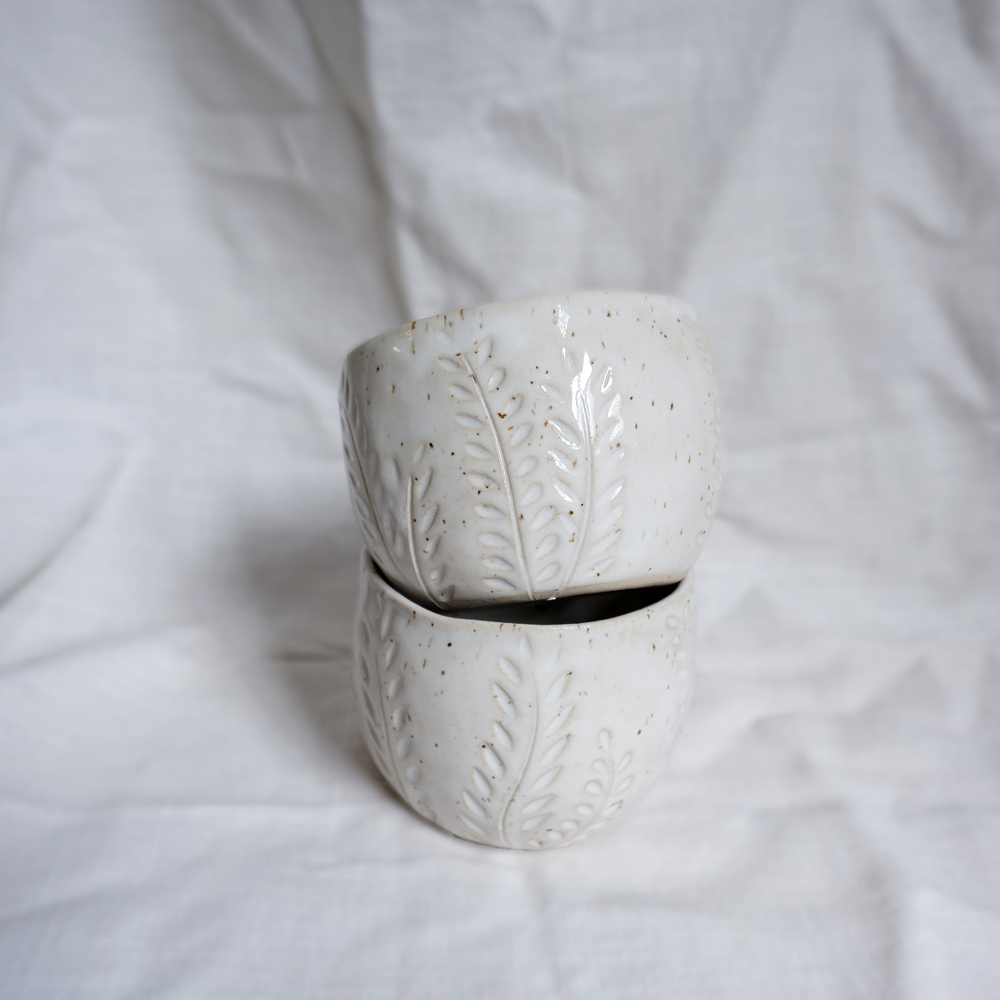 White ceramic cup with leaf patterns on a white background